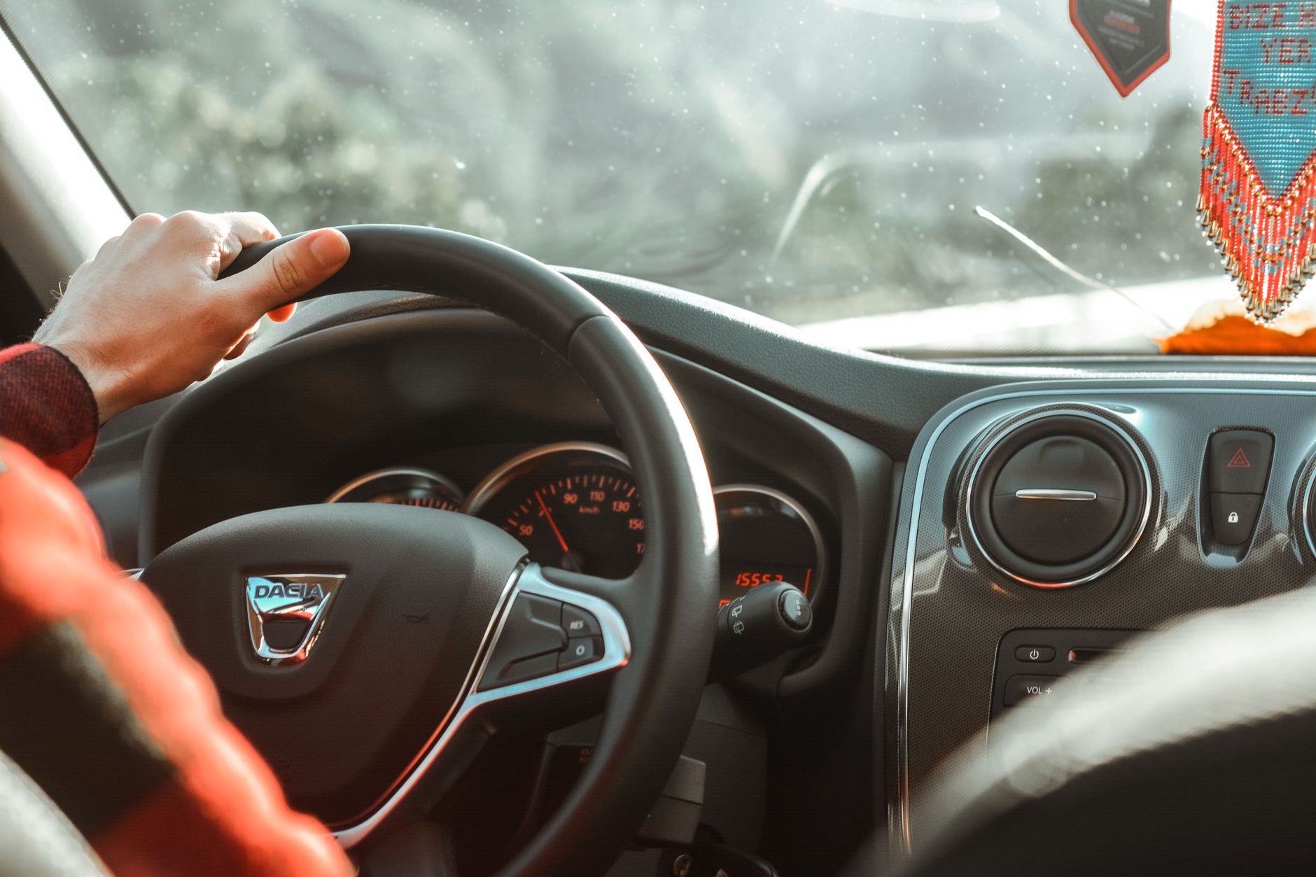 Hands on a steering wheel with the gear stick in reach, the coordination a manual demands
