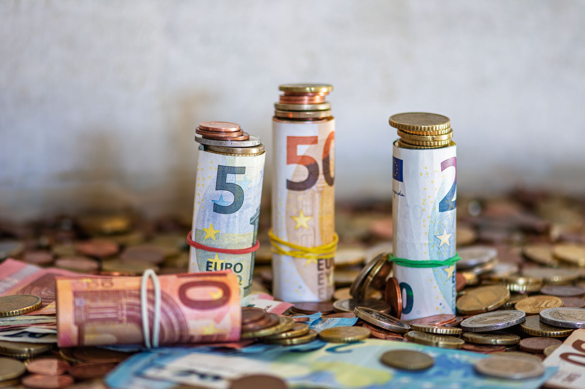 Rolled euro notes and coins on a table, the real cost of the slow route to a driving licence