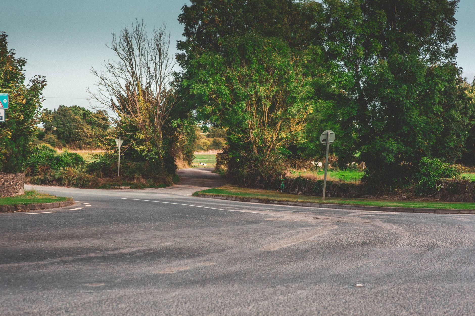 A narrow country road bending through green fields, the sort of blind bend that shows whether a driver is reading the road well ahead