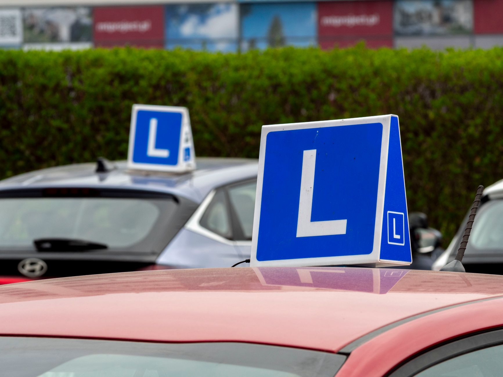 Driving-school cars with learner signs parked in a training area, where the twelve EDT lessons are worked through