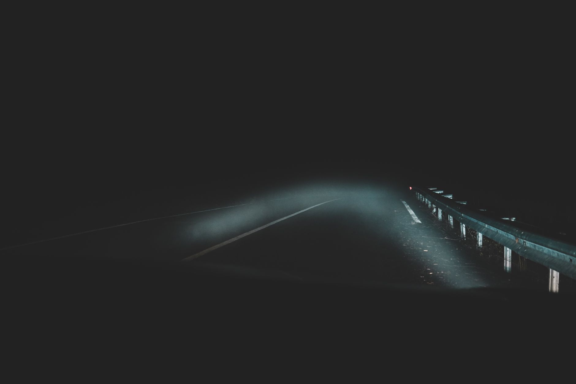 A dark road at night lit only by headlights, where a tired driver's reaction time quietly collapses